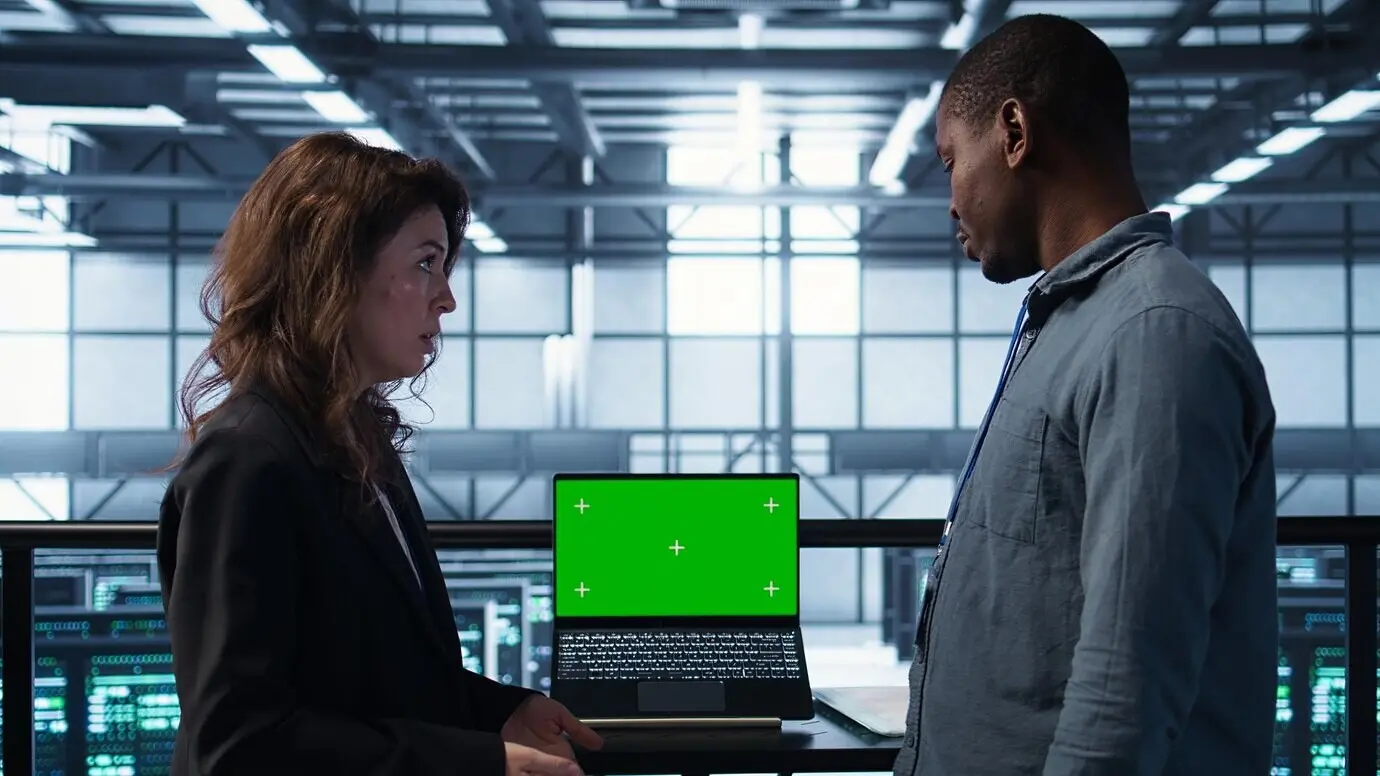 ИТ-эксперты, работающие в команде, настраивают конфигурации серверной с ноутбуком-макетом.